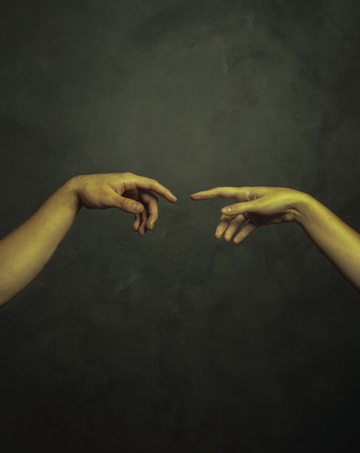 Two hands reaching towards each other against a dark background in an artistic style.
